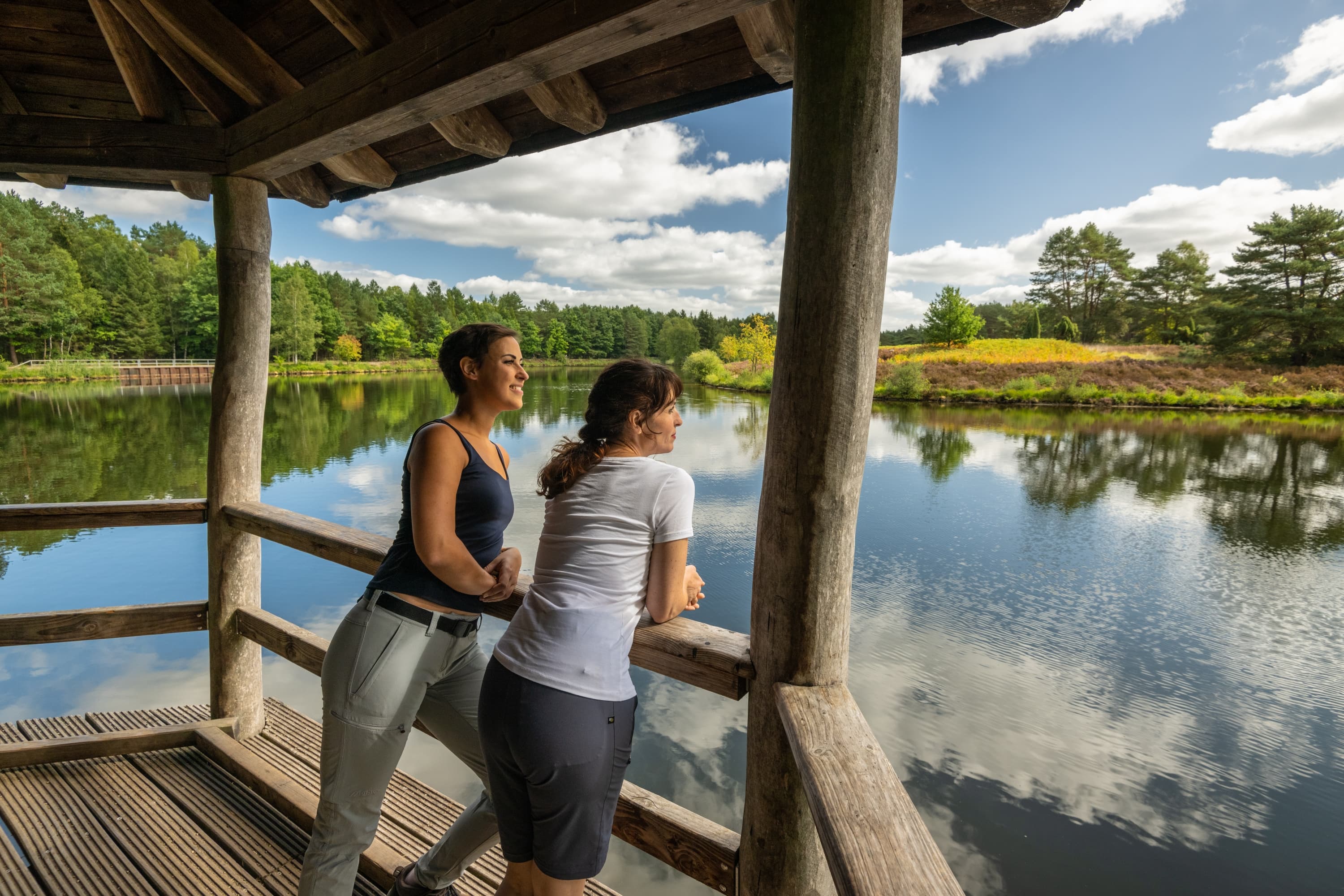 Wanderer am Angelbecksteich zur Heideblüte in Hermannsburg