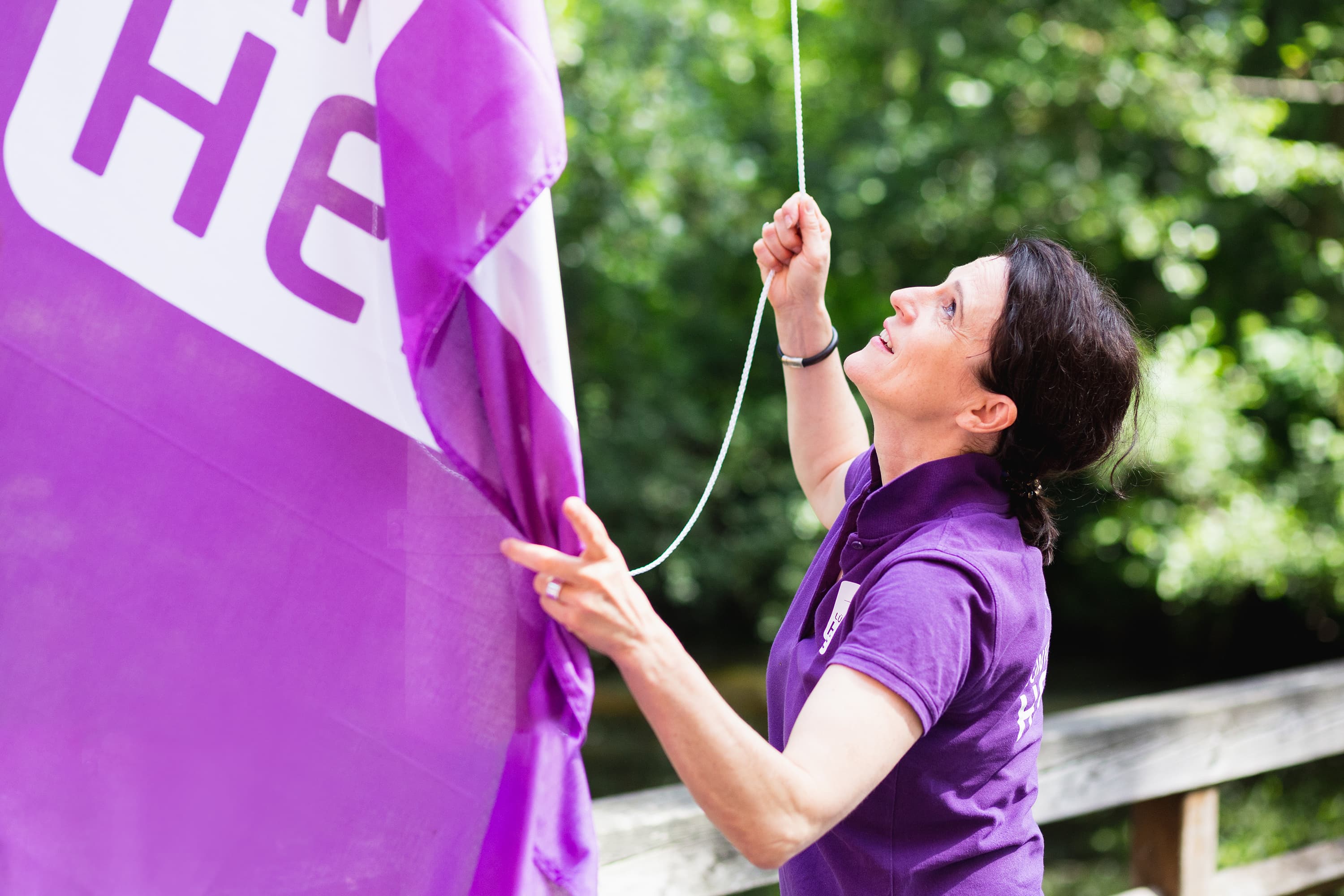 Frau mit lila T-Shirt hisst lila Fahne