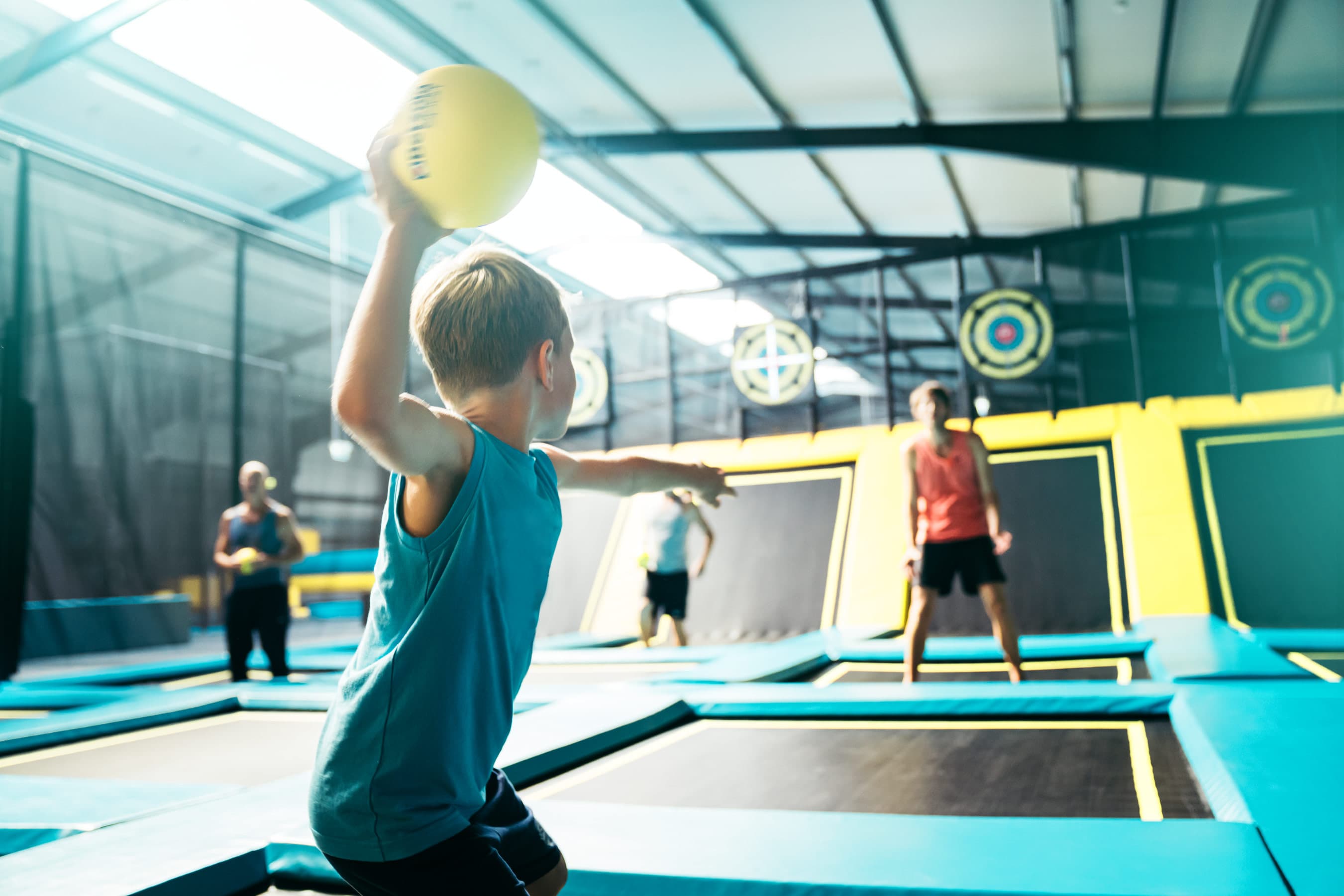 Junge beim Werfen eines Balls auf einem Trampolin in einer Abenteuerspiel- und Trampolinhalle.Boy throwing a ball on a trampoline in an adventure play and trampoline hall.Dreng kaster en bold på en trampolin i en eventyrlege- og trampolinhal.Jongen gooit een bal op een trampoline in een avontuurlijke speel- en trampolinehal.
