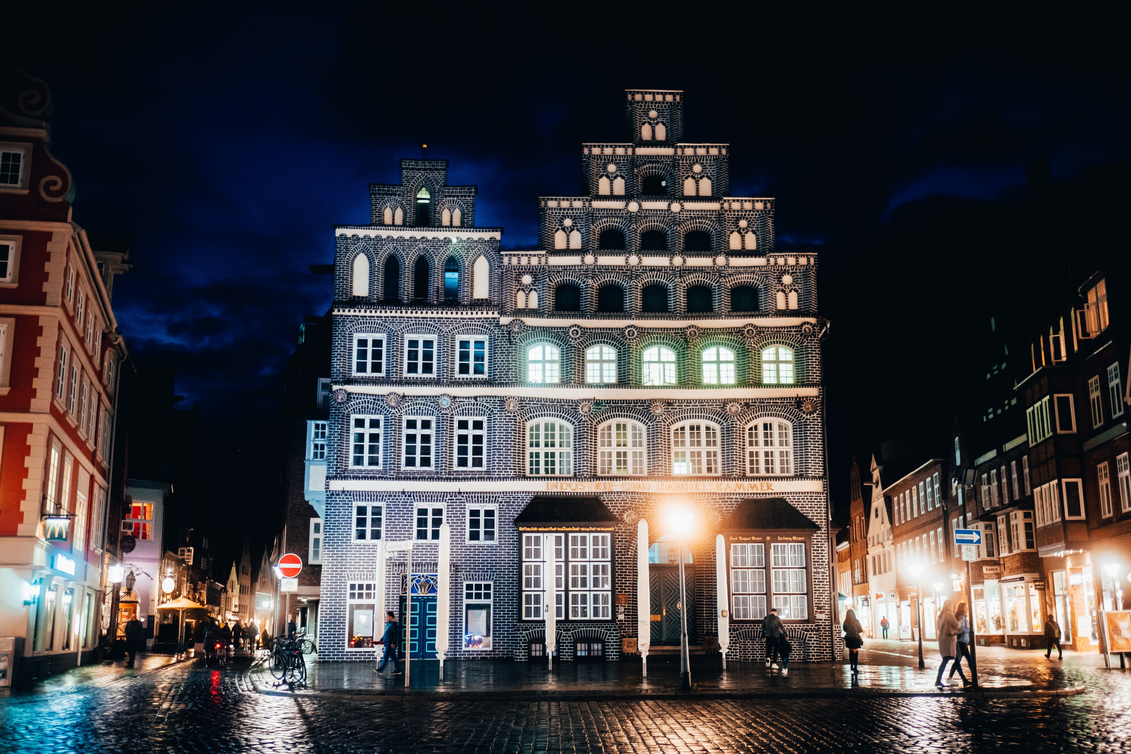 Beleuchtetes historisches IHK-Gebäude mit markanten Treppengiebeln bei Nacht in Lüneburg.