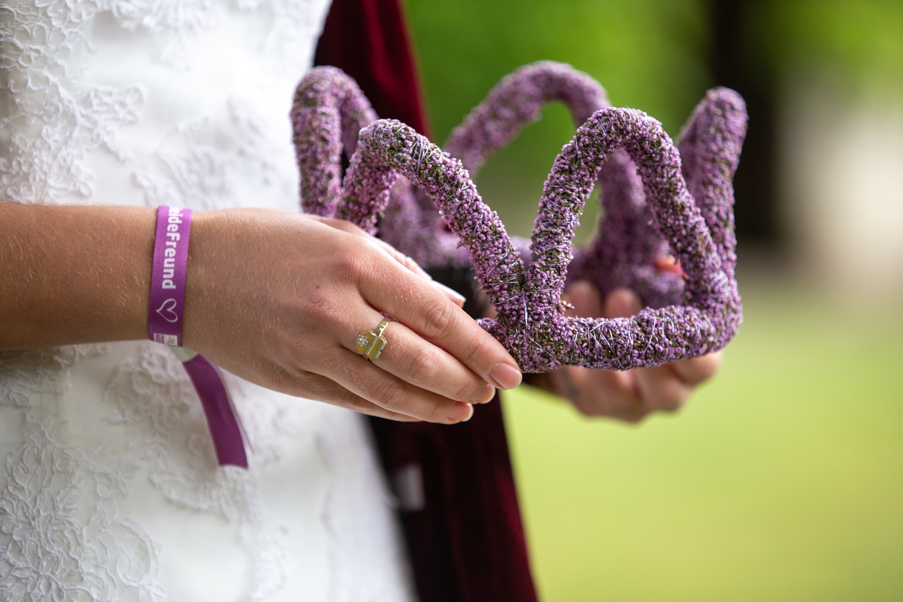 eine Hand mit einem Ring und einer Krone aus Heidekraut