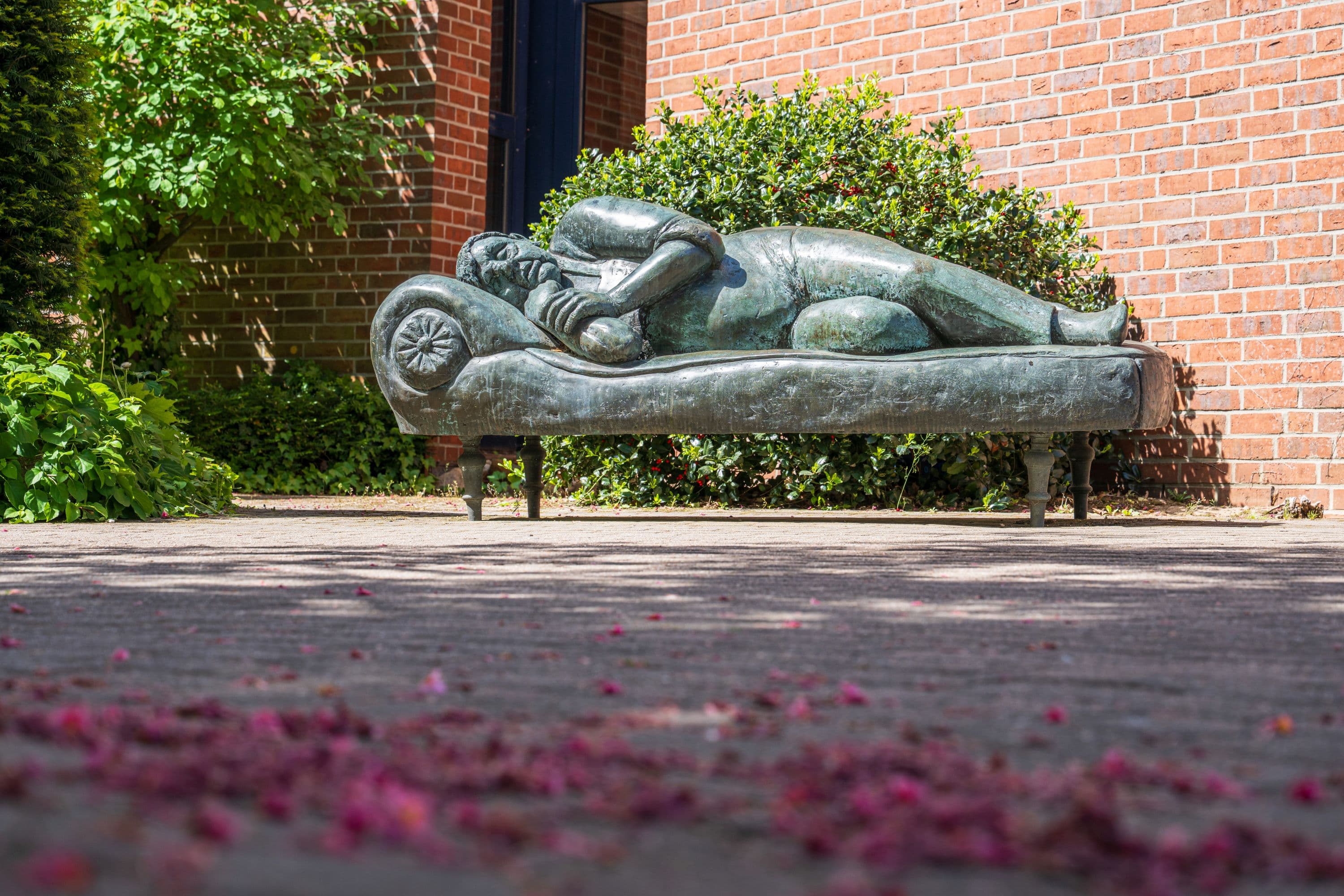 Skulptur eines schlafenden Mannes auf einer Bank in Buchholz in der Nordheide im Frühling