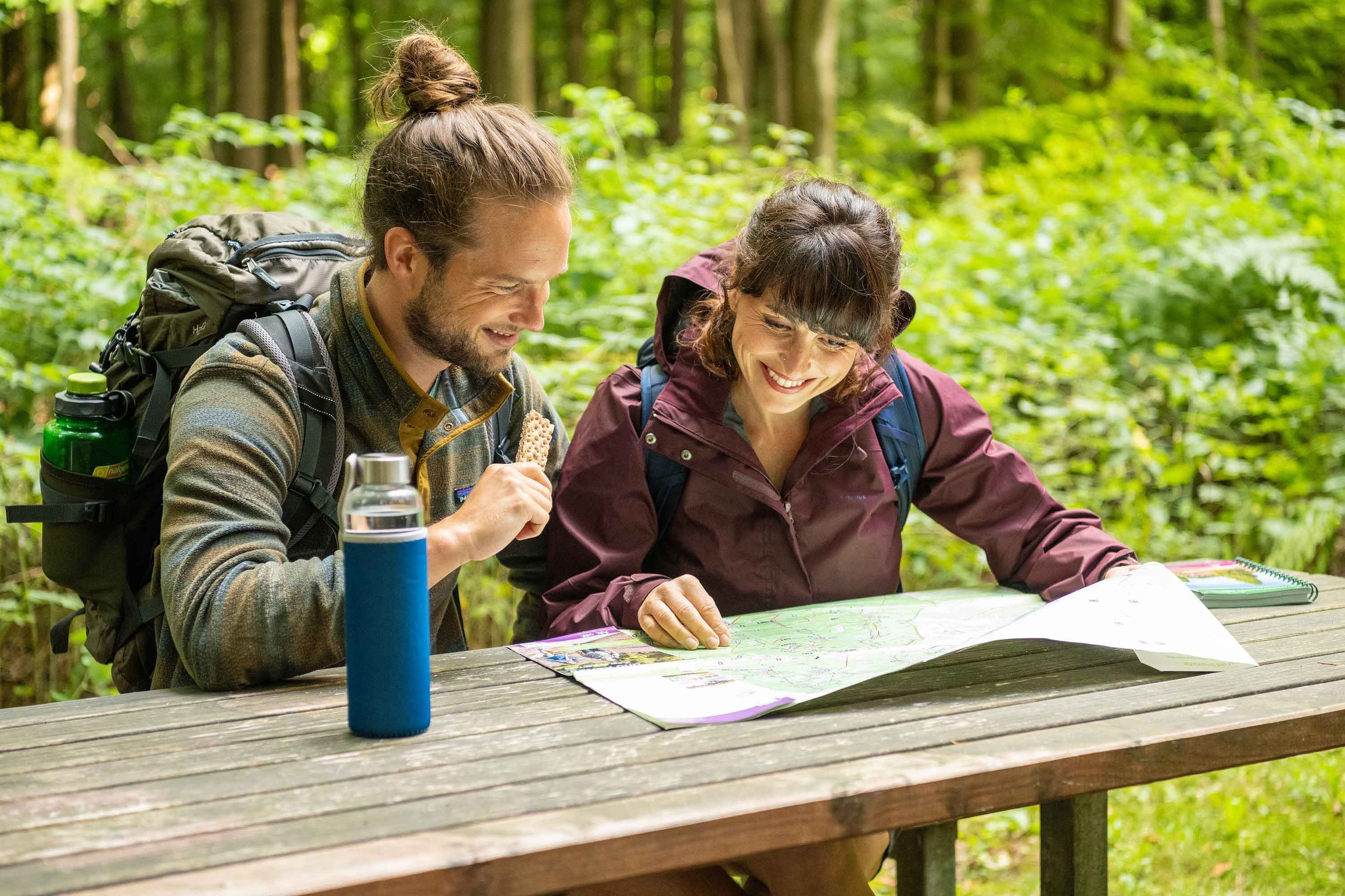 Wanderer planen Route im Luesswald bei Unterluess auf dem Wald Erlebnis Pfad.