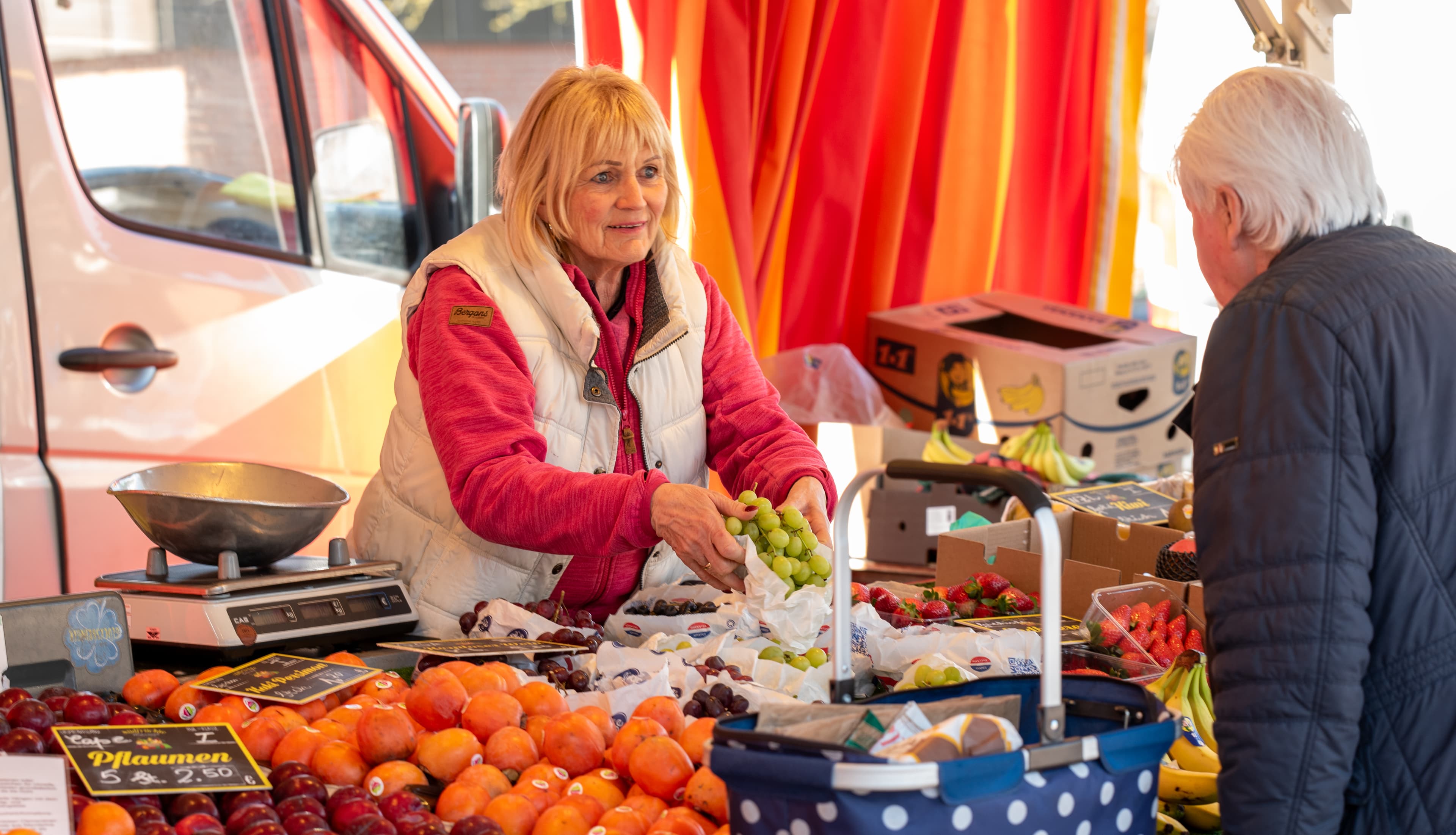 Verkäuferin mit Kundin an einem Obststand