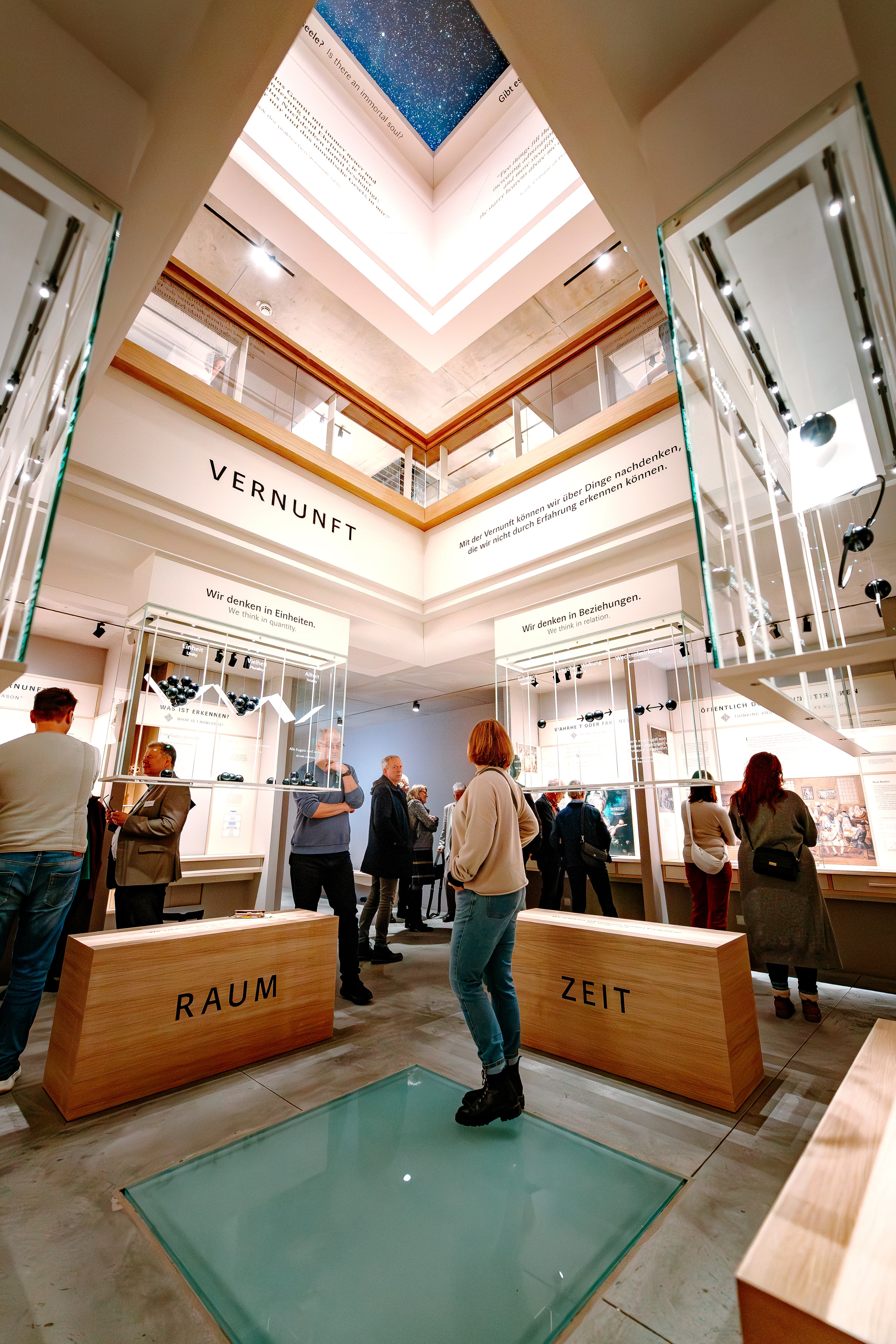 Besucher betrachten helle Vitrinen im Kant-Museum mit großen Begriffen wie Raum und Zeit.