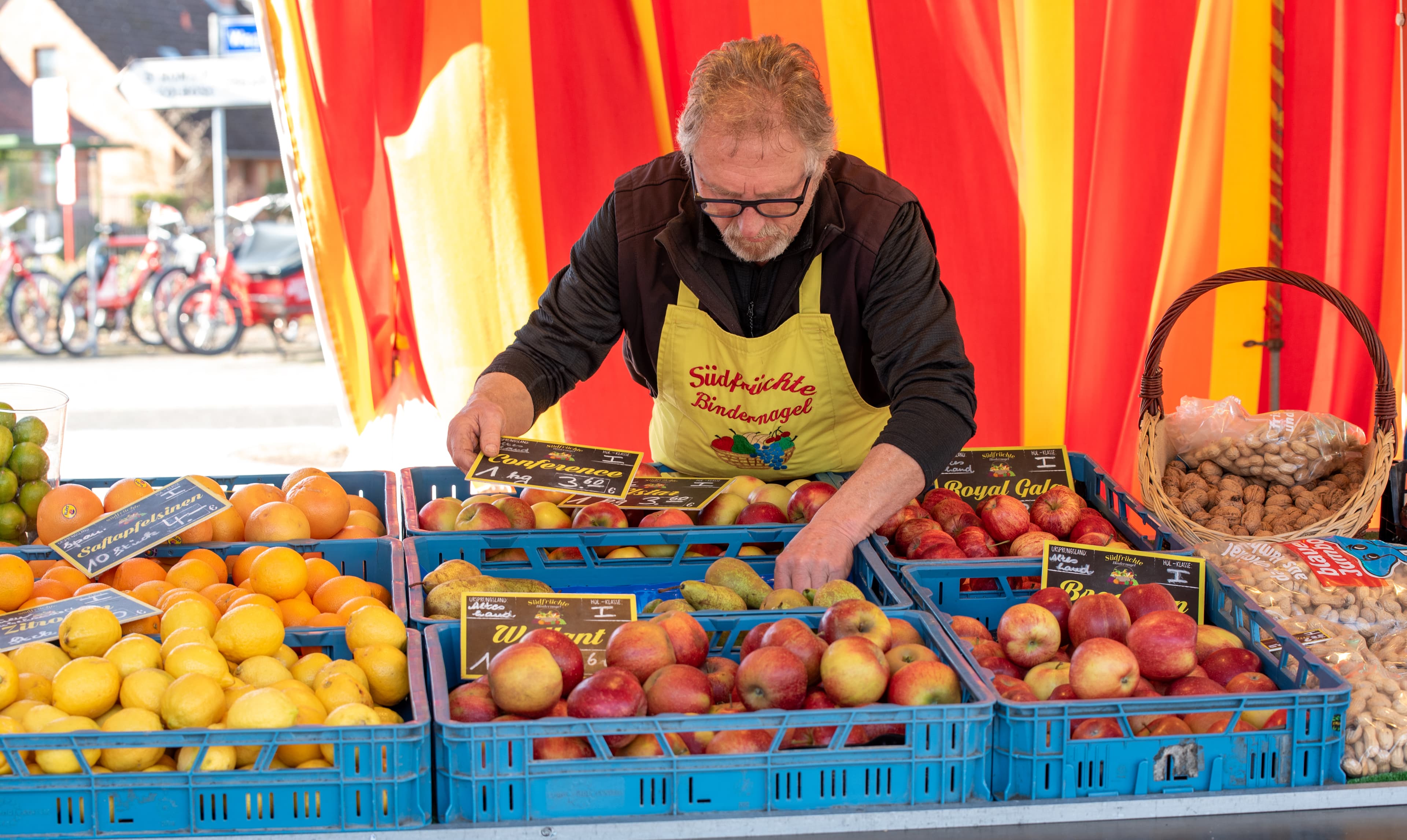 Verkäufer an einem Stand mit Äpfeln, Zitronen und Orangen