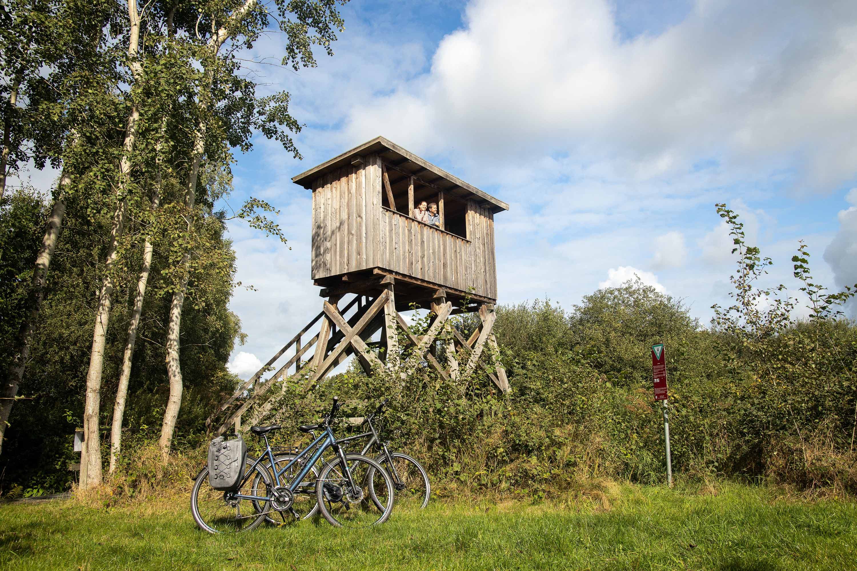 Fahrraeder vor einem hoelzernen Aussichtsturm am Postmoor bei Eldingen in der Suedheide