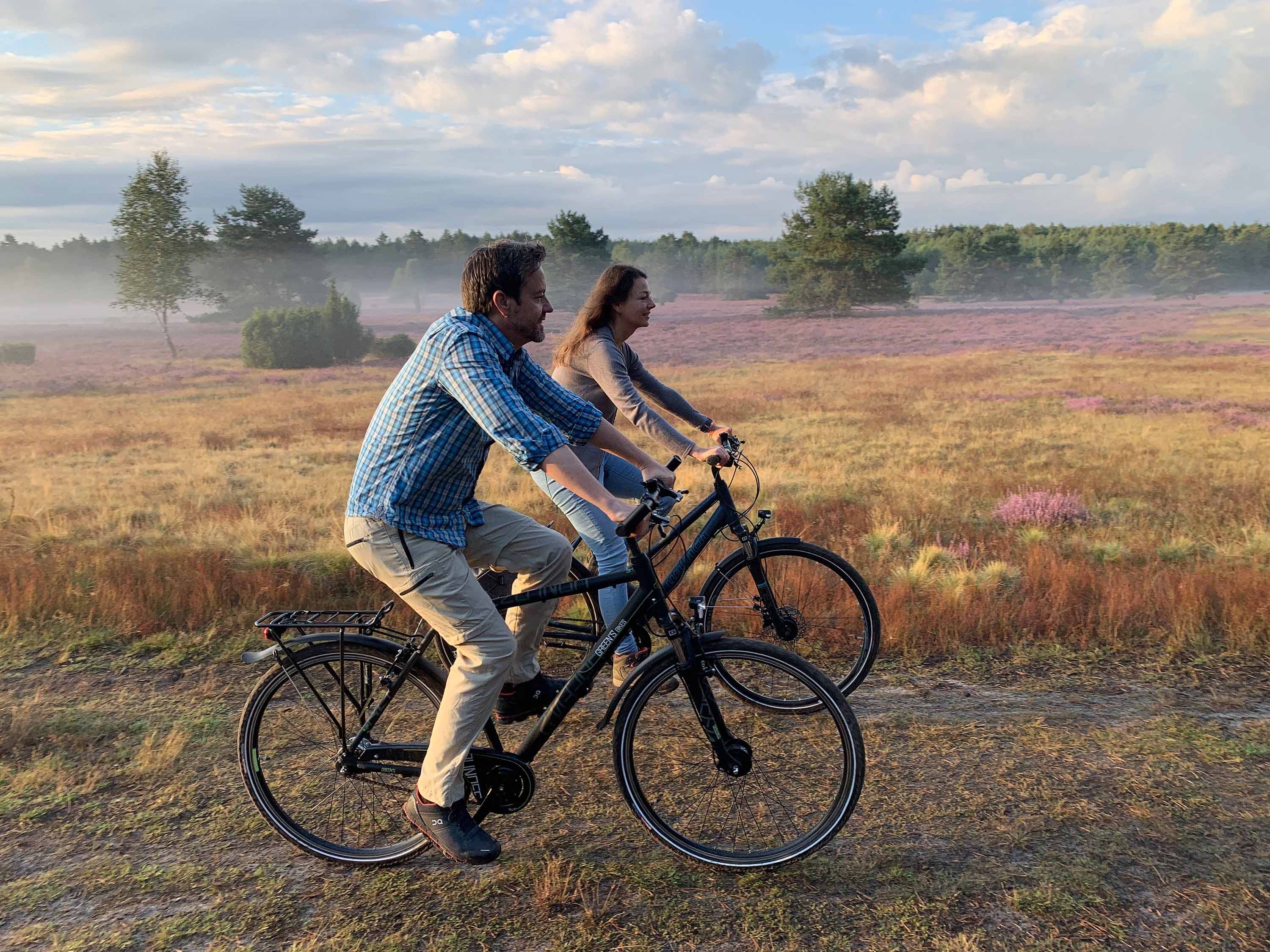Zwei Radfahrer in offener Heidelandschaft am Hausselberg bei Mueden in der Suedheide