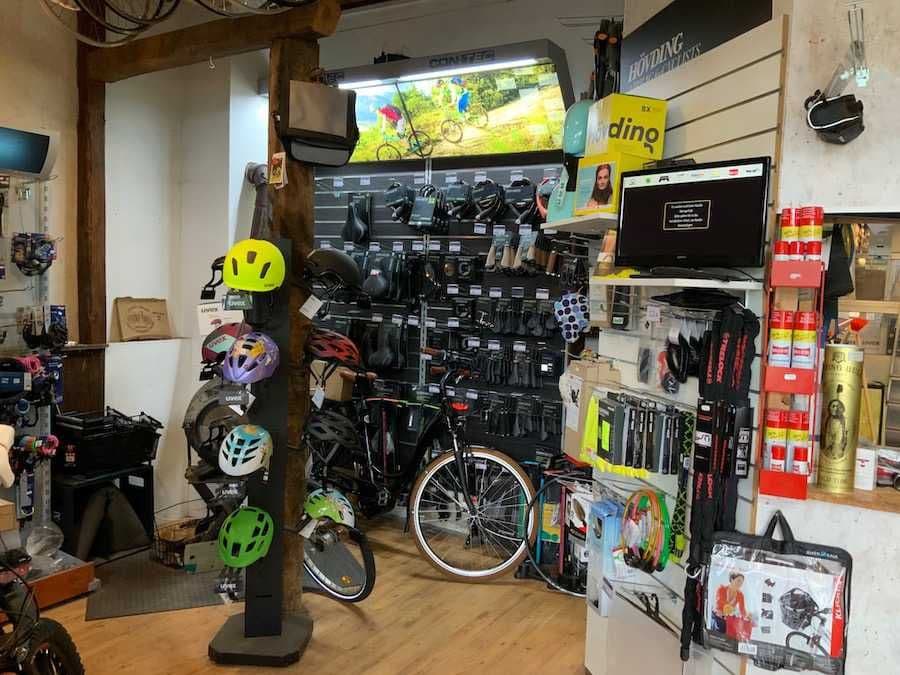 Ein Fahrradladen mit diversen Helmen, Fahrradzubehör und einem Fahrrad an der Wand.A bicycle store with various helmets, bicycle accessories and a bicycle on the wall.